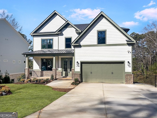 view of front of house featuring concrete driveway, covered porch, a standing seam roof, a front lawn, and brick siding