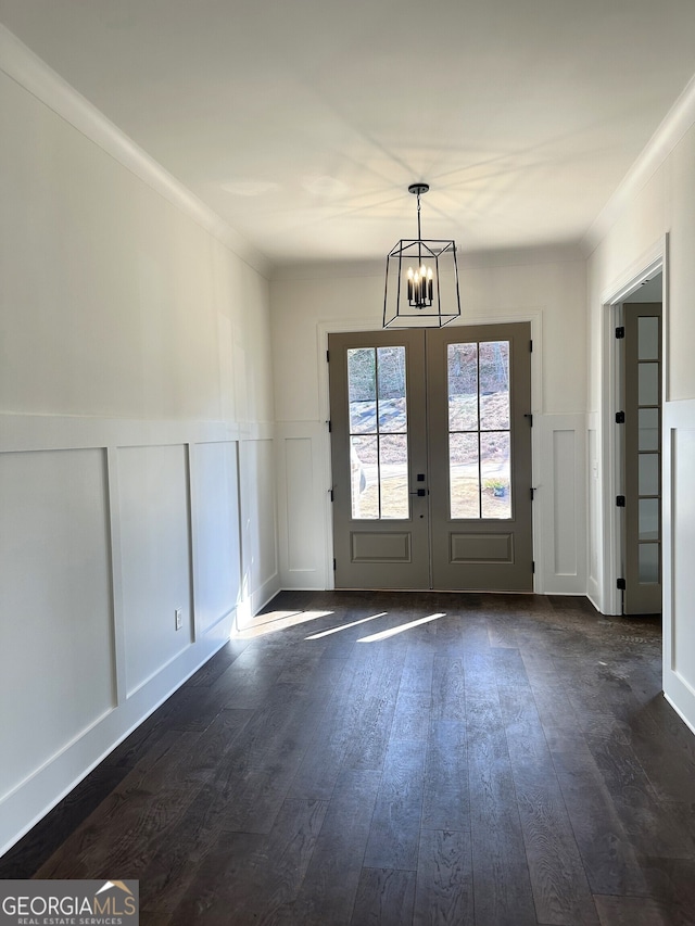 entryway featuring french doors, a decorative wall, dark wood finished floors, and a notable chandelier