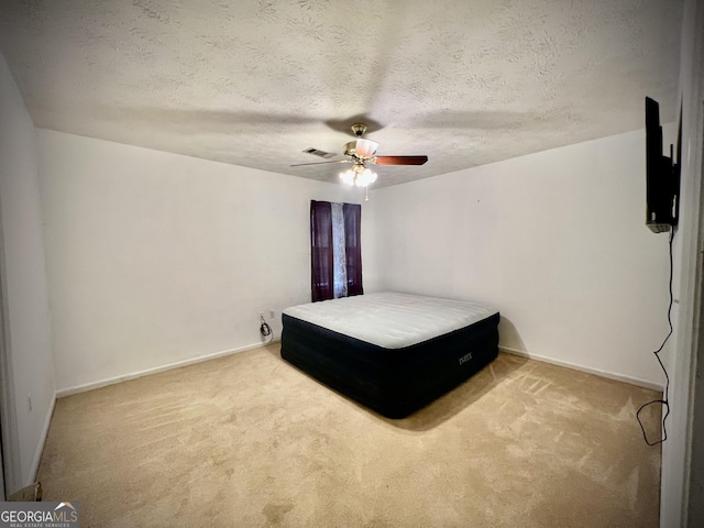 carpeted bedroom featuring a textured ceiling, ceiling fan, visible vents, and baseboards