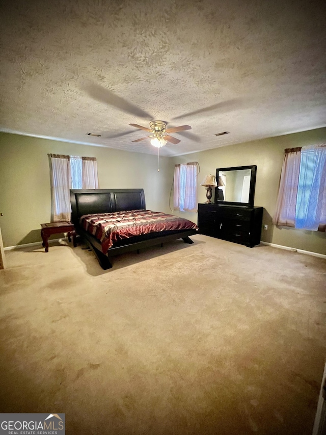 bedroom with a textured ceiling, ceiling fan, and carpet