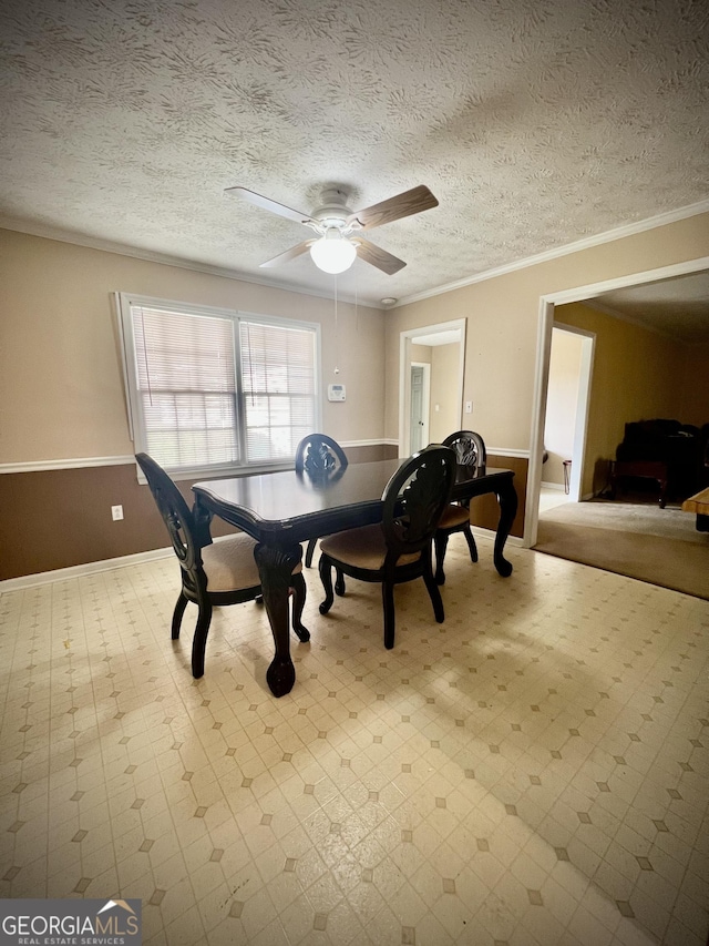 dining area featuring a textured ceiling, a wainscoted wall, a ceiling fan, tile patterned floors, and crown molding