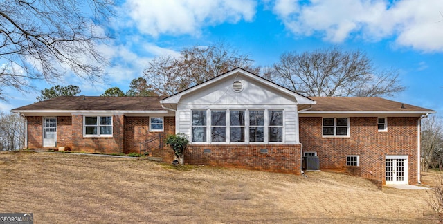 back of property with crawl space, brick siding, a lawn, and central AC unit