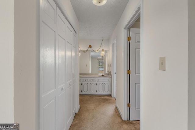 corridor featuring a textured ceiling and light colored carpet