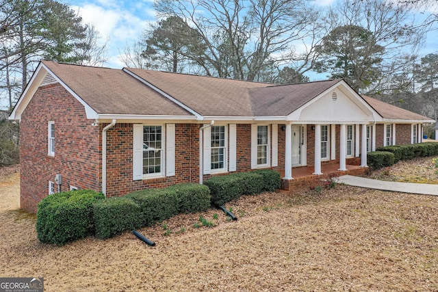 view of front of house with a shingled roof, a porch, and brick siding