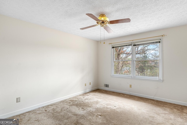 carpeted spare room featuring visible vents, ceiling fan, a textured ceiling, and baseboards