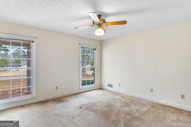 unfurnished room with carpet floors, a ceiling fan, visible vents, and baseboards