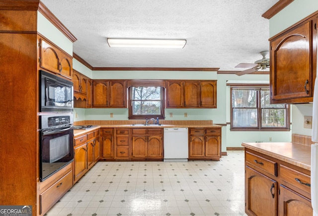 kitchen with light floors, a sink, ornamental molding, black appliances, and brown cabinetry