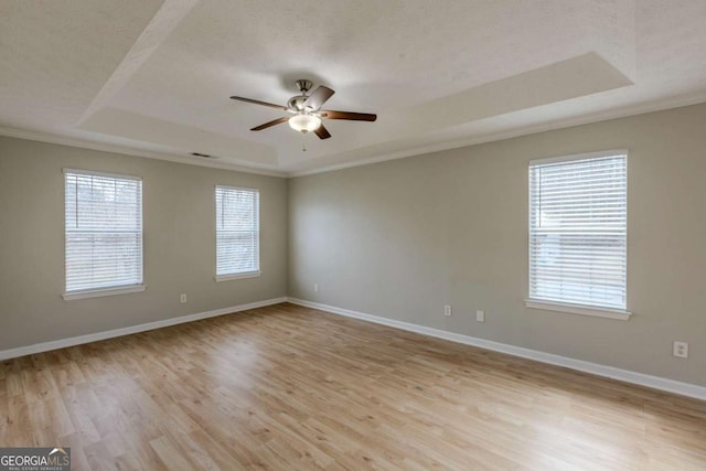 unfurnished room featuring a tray ceiling, ceiling fan, baseboards, and wood finished floors