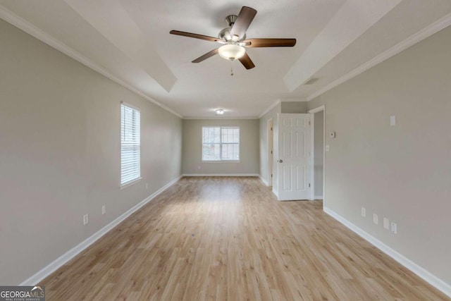 interior space featuring crown molding, light wood finished floors, a raised ceiling, a ceiling fan, and baseboards