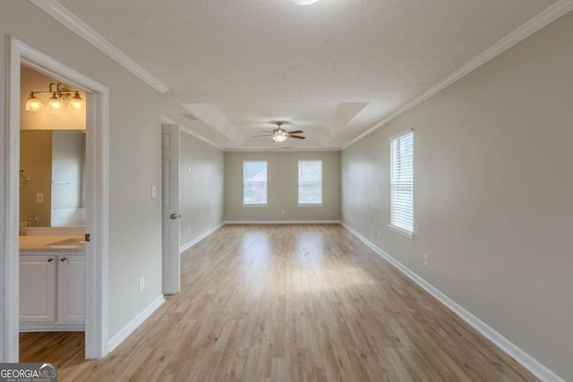 spare room featuring a healthy amount of sunlight, light wood finished floors, baseboards, and ornamental molding