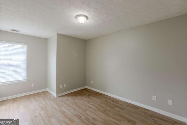 empty room featuring a textured ceiling, baseboards, and wood finished floors