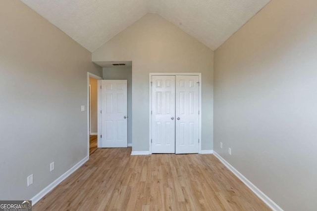 unfurnished bedroom featuring high vaulted ceiling, visible vents, baseboards, light wood-style floors, and a closet