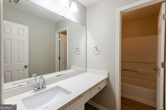 full bath featuring visible vents, vanity, a bathing tub, and wood finished floors