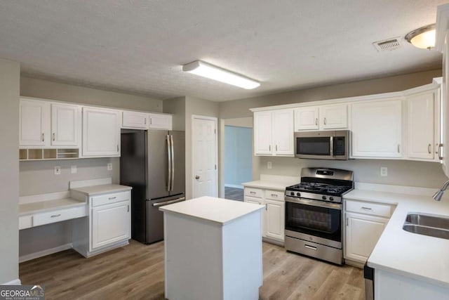 kitchen with visible vents, light wood-style flooring, stainless steel appliances, white cabinetry, and a sink