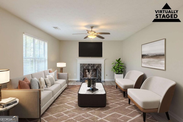 living area with ceiling fan, a fireplace, visible vents, and baseboards