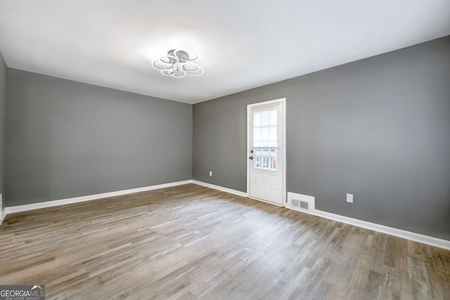 unfurnished room featuring visible vents, baseboards, and wood finished floors