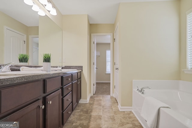 bathroom featuring double vanity, a sink, a bath, and baseboards