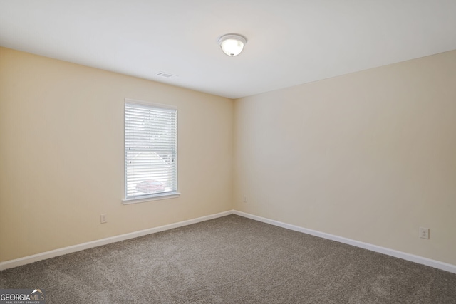 spare room featuring carpet, visible vents, and baseboards