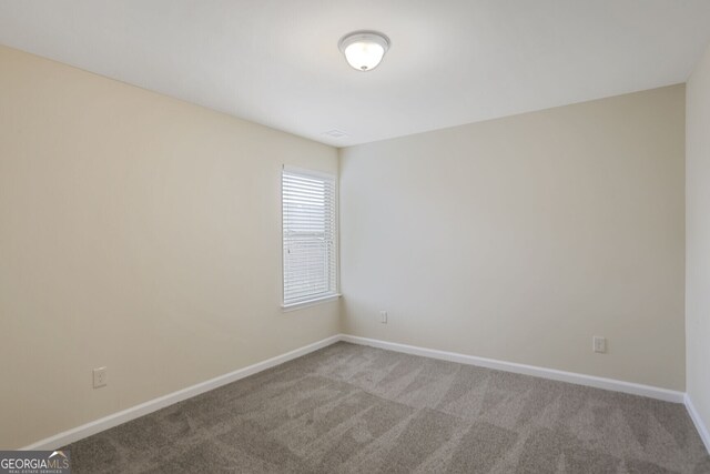 unfurnished room featuring carpet and baseboards