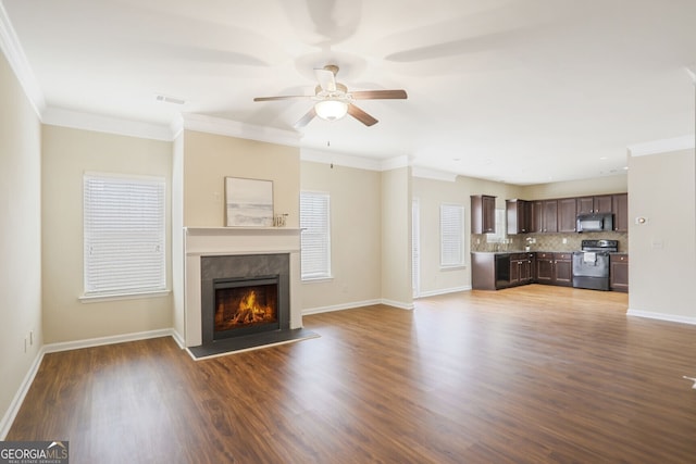 unfurnished living room featuring baseboards, crown molding, visible vents, and wood finished floors