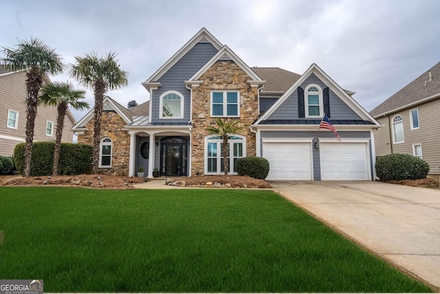 view of front of house with a standing seam roof, a front lawn, driveway, and stone siding