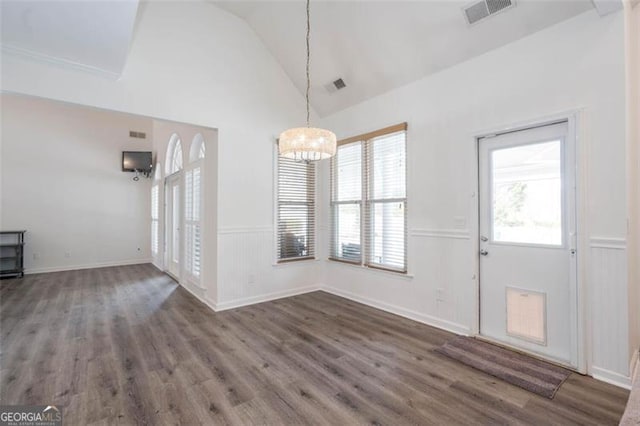 unfurnished dining area featuring wood finished floors, visible vents, a wainscoted wall, and high vaulted ceiling