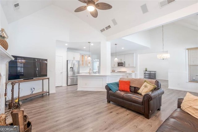 living room with visible vents, high vaulted ceiling, and ceiling fan with notable chandelier