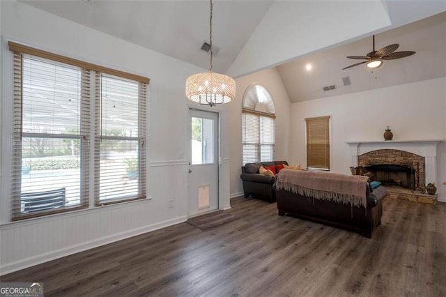 interior space with a fireplace, visible vents, a ceiling fan, wood finished floors, and high vaulted ceiling