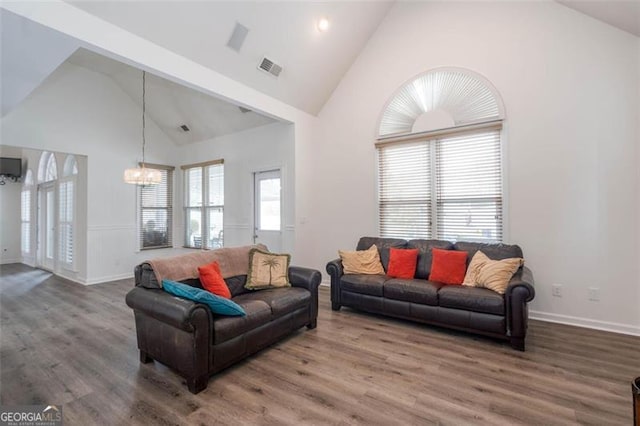 living room with a chandelier, high vaulted ceiling, wood finished floors, and baseboards