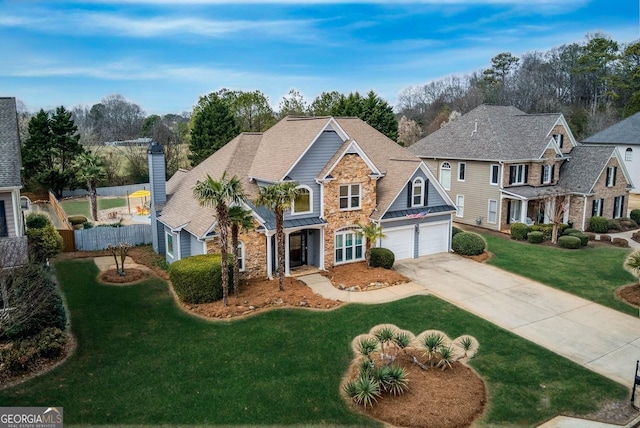 traditional home with fence, a garage, stone siding, a front lawn, and concrete driveway