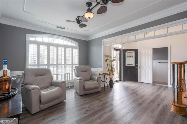 sitting room featuring ceiling fan, visible vents, wood finished floors, and ornamental molding