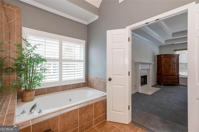 bathroom with a fireplace with flush hearth, crown molding, a bath, and tile patterned flooring