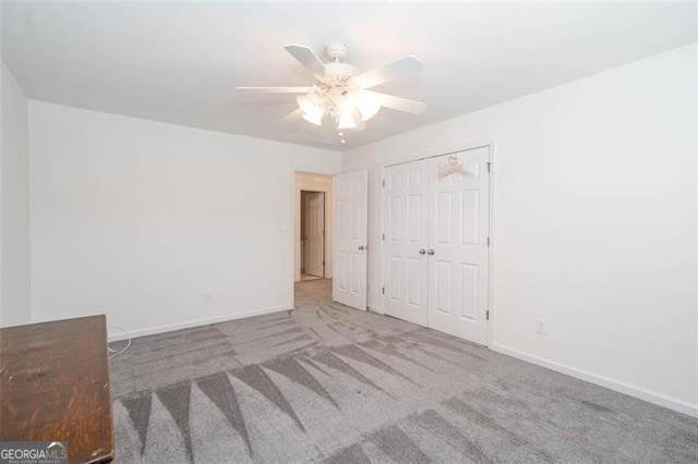 unfurnished bedroom featuring ceiling fan, a closet, carpet flooring, and baseboards