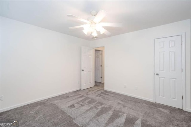 carpeted spare room with a ceiling fan and baseboards