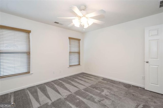 empty room with baseboards, visible vents, ceiling fan, and carpet flooring