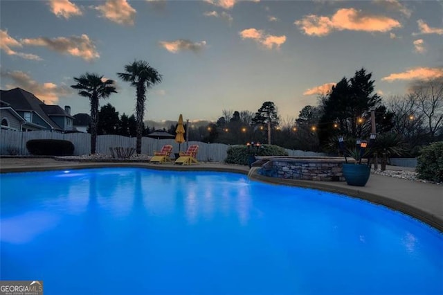 pool at dusk featuring fence and a fenced in pool