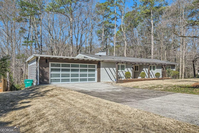 mid-century home with driveway, an attached garage, a front lawn, and brick siding