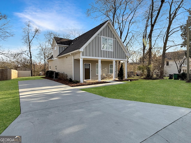 view of front of home featuring covered porch, board and batten siding, fence, driveway, and a front lawn