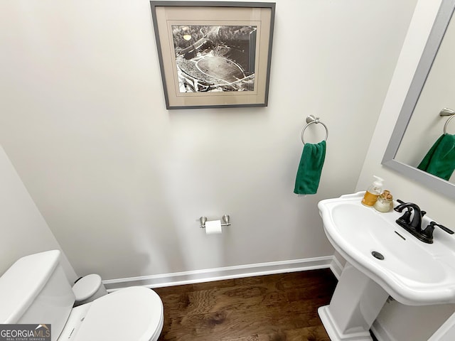 half bath featuring toilet, baseboards, and a sink