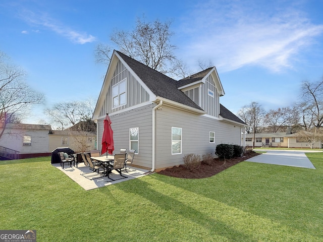 view of side of home featuring a yard, a shingled roof, board and batten siding, and a patio area