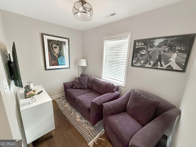 living room with dark wood finished floors, visible vents, and baseboards