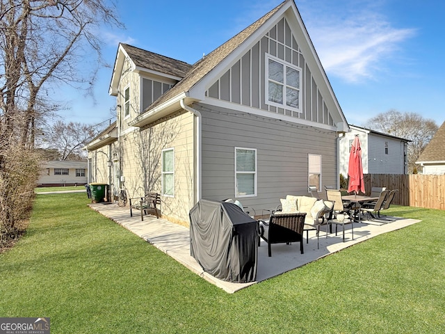 rear view of property featuring board and batten siding, a yard, a patio area, and fence