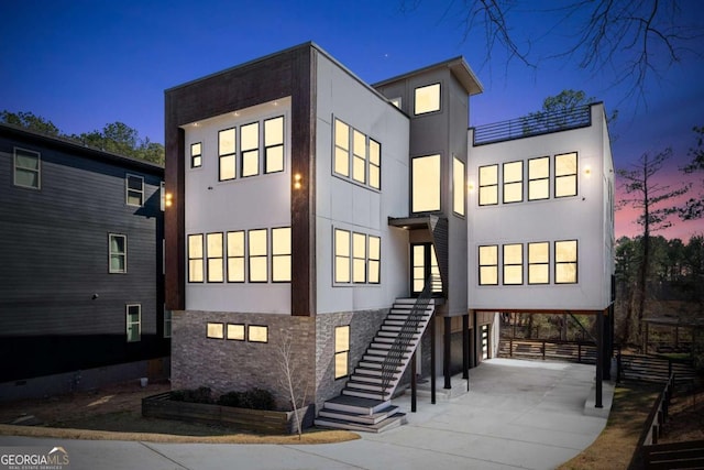 view of front facade with concrete driveway, stairs, stucco siding, a carport, and stone siding