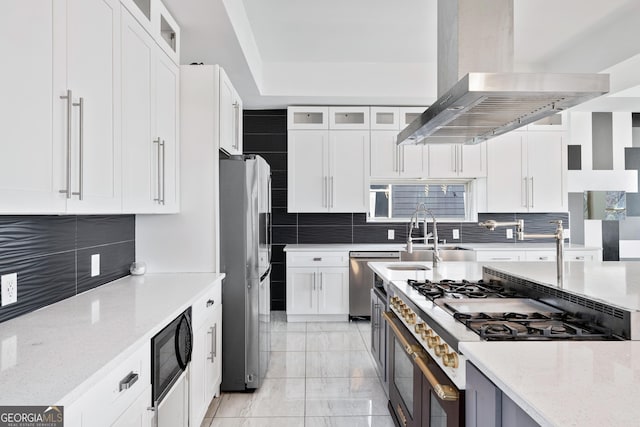 kitchen with tasteful backsplash, stainless steel appliances, wall chimney range hood, and a sink