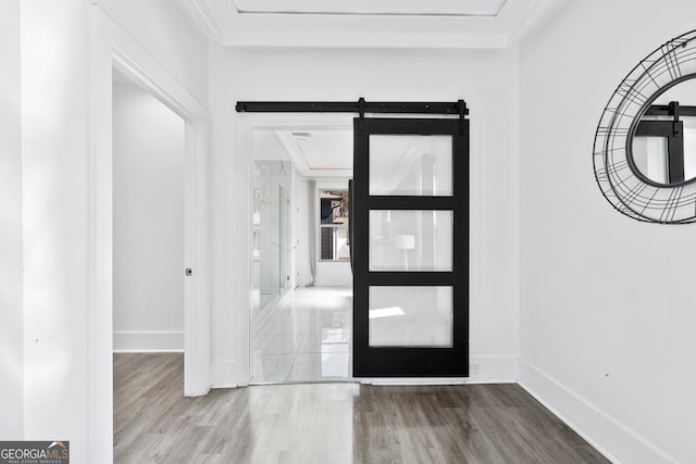 foyer entrance with a barn door, baseboards, and wood finished floors