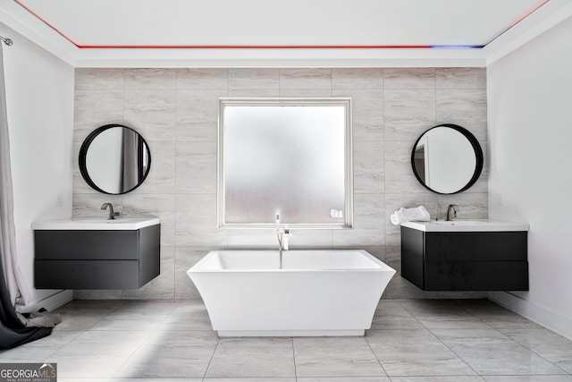 full bathroom featuring a sink, a freestanding bath, tile walls, and two vanities