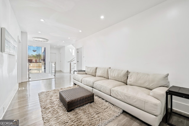 living room featuring recessed lighting, light wood-style flooring, stairs, and baseboards