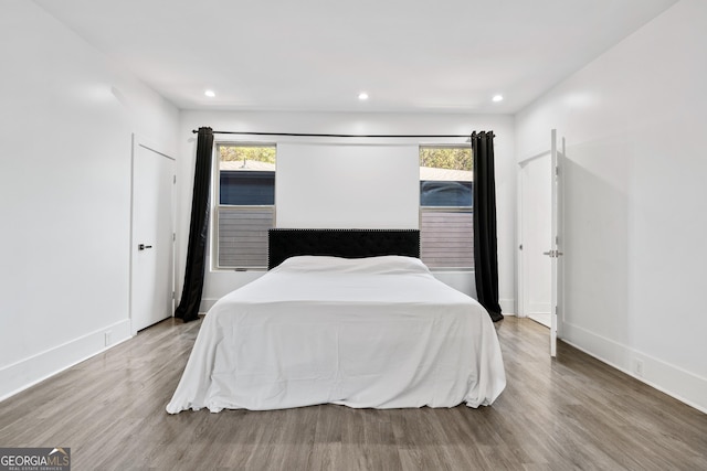 bedroom featuring recessed lighting, baseboards, multiple windows, and wood finished floors