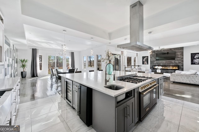 kitchen featuring range with two ovens, a fireplace, island exhaust hood, a sink, and open floor plan