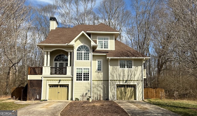 view of front of property featuring concrete driveway, a chimney, an attached garage, and a balcony